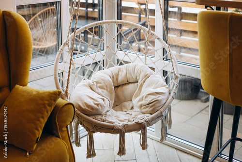 Hanging chair in cozy modern café interior with warm light.
