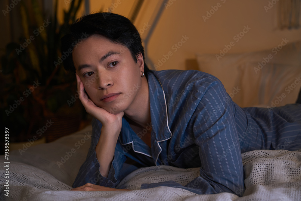Obraz premium Asian man relaxing in his stylish modern apartment during nighttime hours