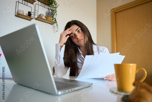 Stressed woman holding papers feeling headache burnout