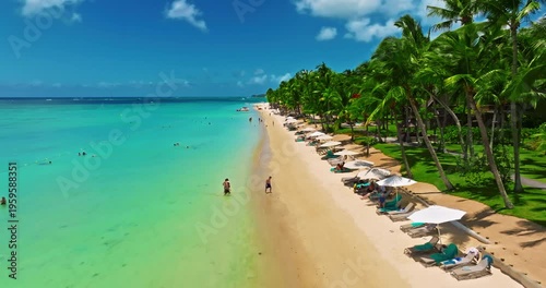 Aerial view of beach with palm trees and perfect turquoise sea water. Relaxing and exotic drone view of a tropical coastline. Luxury summer vacation and holiday concept