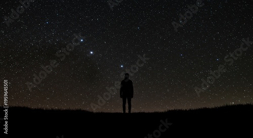 Solitary silhouette stands beneath a brilliantly star-filled night sky