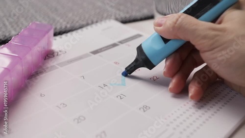 hand marks calendar for pill intake, medication schedule planning and adherence tracking