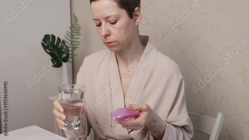 cancer patient holds pill organizer and water glass, managing long-term therapy routine at home