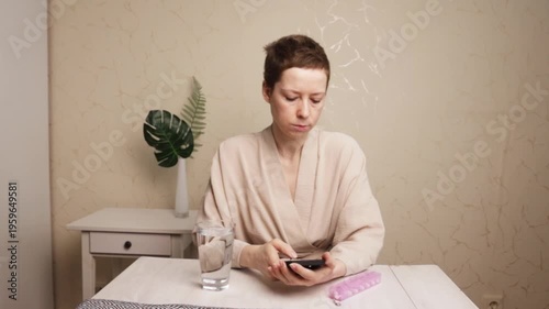 cancer patient uses smartphone with pill organizer, marking medication as taken and tracking routine