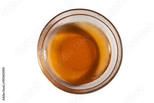 Fotografía Amber viscous syrup texture in transparent glass bowl macro shot