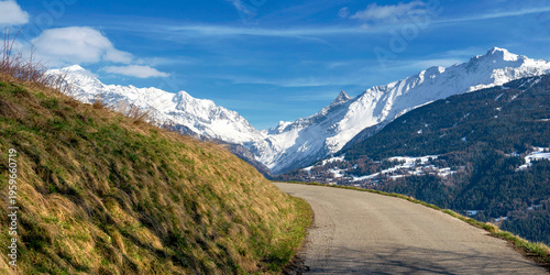 mountain road along a hill with a view of the surrounding snowy mountain peak...