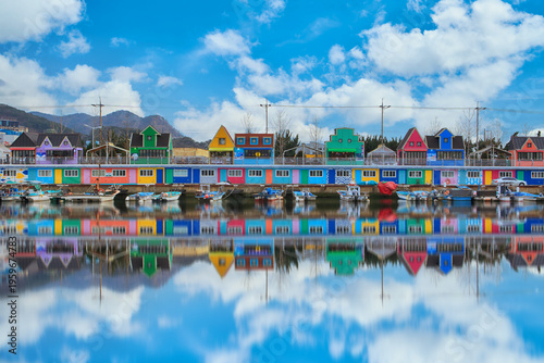 Colorful houses of Jangnim Port Busan known as Korean Venice with fishing boats and reflection on calm water under blue sky. Scenic harbor village and popular travel destination.