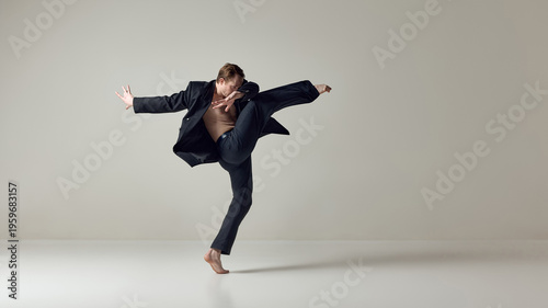 Fotografía Male dancer executing powerful high kick with dynamic upper body motion in studio