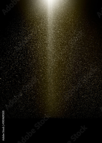 Golden light beam illuminates falling dust particles on a black background