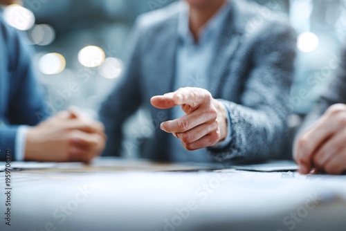 Businessman aggressively pointing his finger across a table during a serious meeting while colleagues listen intently in a modern corporate environment