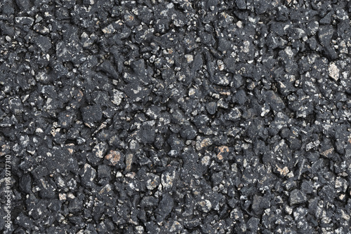 Close-up view of weathered asphalt pavement showing rough gravel, aggregate and cracks. A textured blacktop surface ideal for backgrounds, design overlays, construction or urban and industrial themes