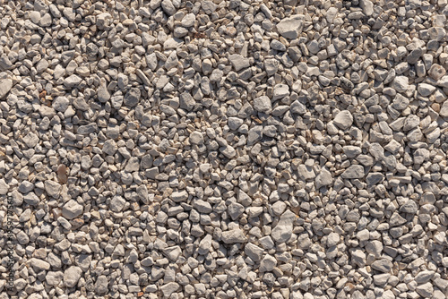 Closeup aerial view of light-colored gravel forming a textured background ideal for landscaping, pathways, construction aggregate and natural material design. Background photo texture