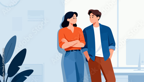 Two people stand in a bright, modern office space. One person wears a red shirt and blue jeans, arms crossed. The other, in a blue jacket, smiles warmly with a relaxed posture