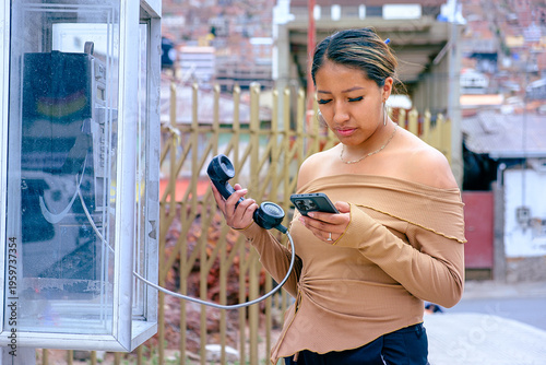 Canvastavla A dark-skinned Latina woman looking at a modern smartphone while holding an old-