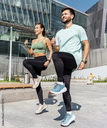 Fit man and woman exercising with high knees in an urban setting on a sunny day
