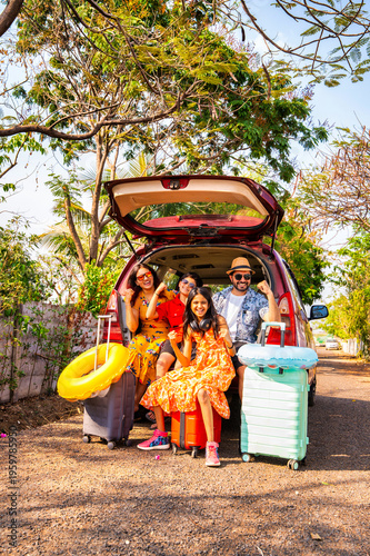 Young Indian parents and kids cheering in a car trunk for a family vacation