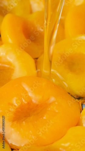 Slow motion of pouring sugar syrup on canned peaches