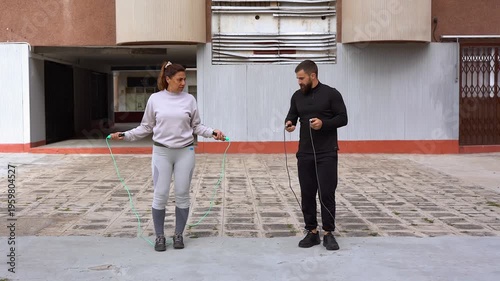 Personal trainer and mature latin woman doing jumping rope exercise outdoor - Sport, workout and healthy lifestyle concept