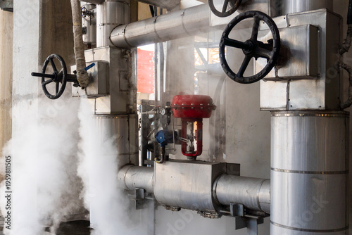 Photography Steam escapes from industrial pipes and valves in factory setting