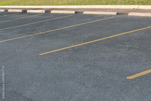 Empty asphalt parking lot with yellow lines and concrete curbs on a sunny day