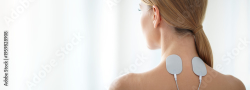 Transcutaneous electrical nerve stimulation device on upper back, physiotherapy treatment, pain relief therapy, electrical muscle stimulation, TENS therapy application, rehabilitation session