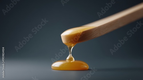 Amber wax drips from a wooden applicator