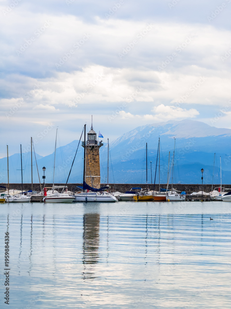 Fototapeta premium Garda lake, Italy. Lighthouse in the port of Desenzano del Garda. Yachts and boats moored in the port.