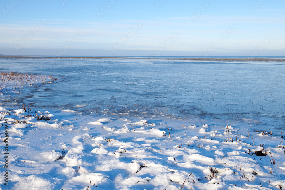 Obraz premium Landscape, blue sky and ocean with snow in nature for climate change, winter season and morning frost. Space, sea and coastline with ice formation, frozen field and icy conditions from global warning