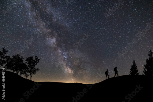 Canvas Print Lone person standing on top of rock, pointing with hand towards the Milky Way and the vast expanse of universe