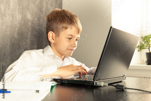 A schoolboy boy studies at home and does school homework. 
