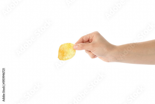 Fotografija Hand holding a single crispy golden potato chip against a dark surface
