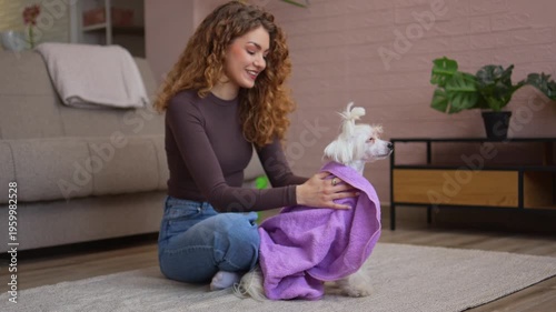 Young woman lovingly drying her small dog with a towel