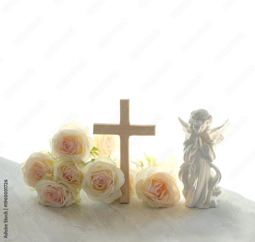 Obraz premium Easter holiday background. Beautiful angel figurine with wooden cross and rose flowers on light table close up. symbol of Easter, Christianity religion, faith in God, prayer, memory. soft focus