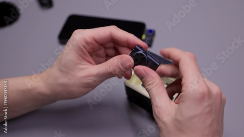 Close-up hands of newsman examining modern wireless microphone system, opening charging case, checking transmitter and accessories before connecting to smartphone for recording, close-up, slow motion.