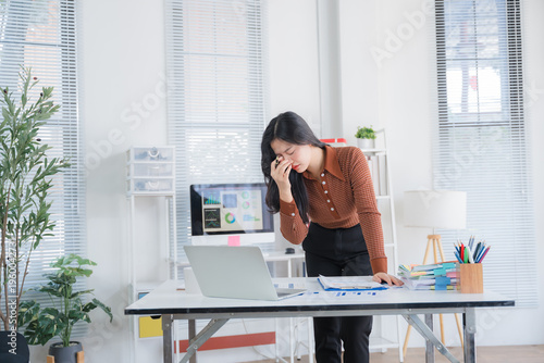 Young Asian businesswoman working on laptop computer, stressed has a headache and thinks hard from work at the office