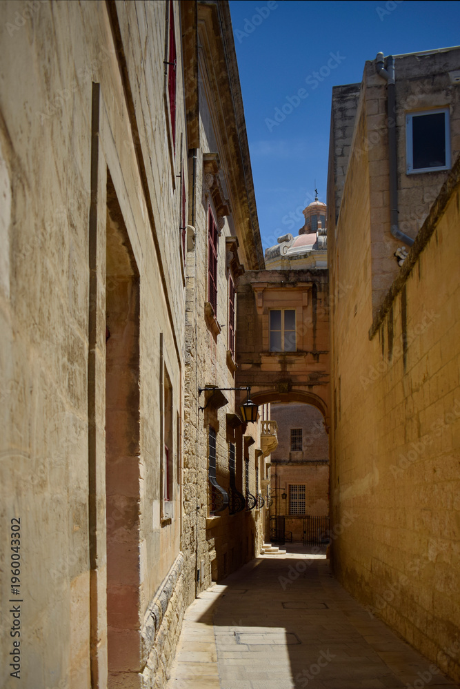 Fototapeta premium Historic Narrow Alley in Mdina Malta with Stone Walls and Dome