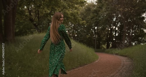 Young beautiful woman walking in long green dress at summer nature. Caucasian European happy girl run with smile in park. Amazing natural women beauty, long blond straight hair. Ukrainian people 4k