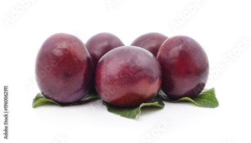 Ripe purple plums with green leaves.