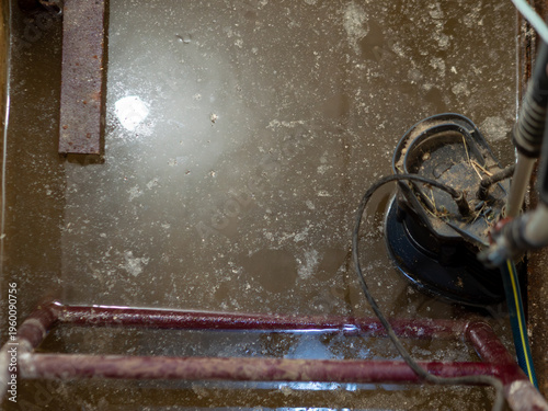 фотографія Close up overhead view of black electric submersible water pump working in murky flooded concrete pit with surface bubbles for home basement drainage and flood prevention