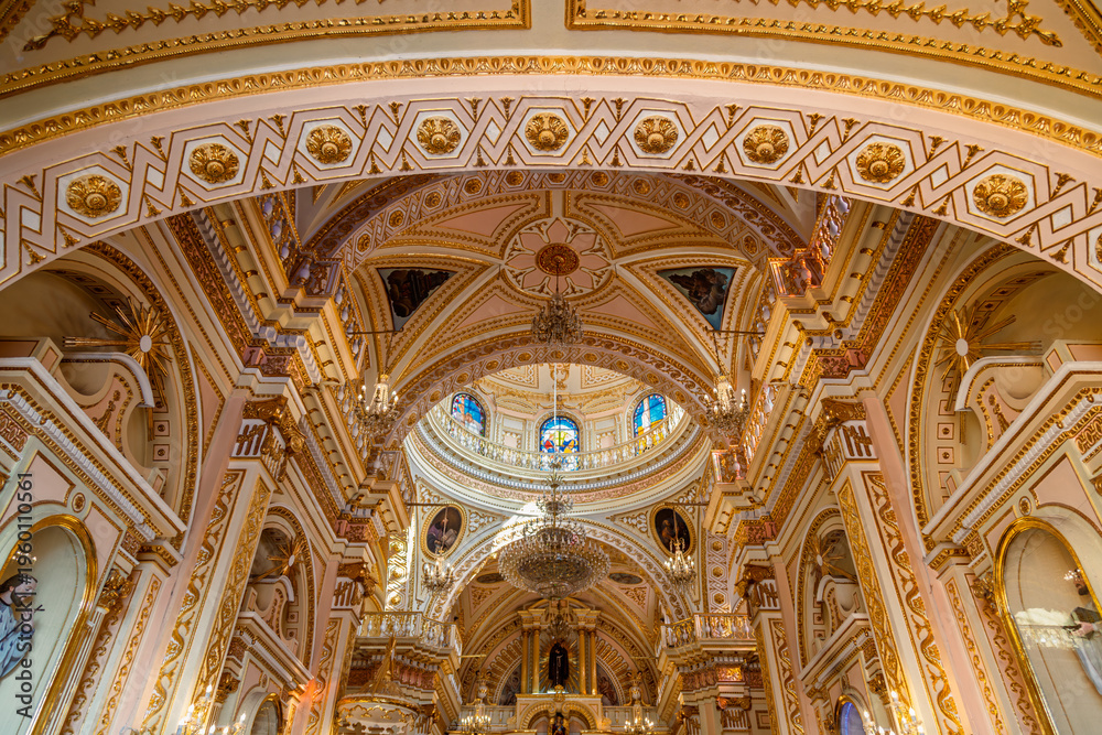 Obraz premium Ornate pink and gold arched ceiling with geometric patterns and stained glass dome inside Sanctuary of Nuestra Señora de los Remedios in Cholula, Puebla, Mexico