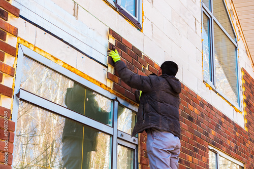 Photography A man works with a drill, attaches thermal panels made of clinker