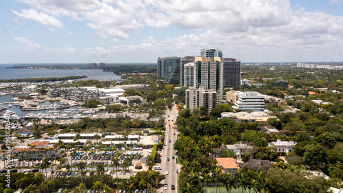 A wide drone view reveals Coconut Grove’s tree-lined streets and waterfront skyline set against the calm waters of Biscayne Bay.