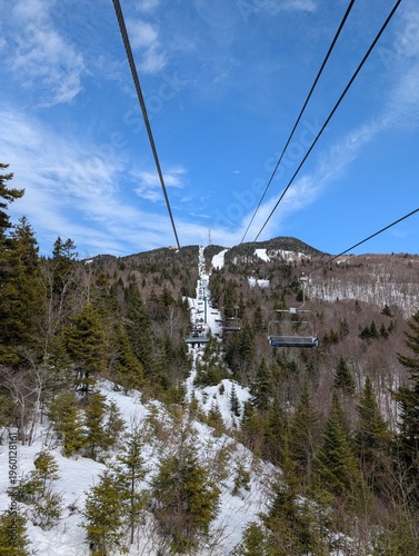 Skiing in winter - chairlift and ski slopes for skiing and snowboarding  between trees on a frosty day with beautiful views in  mountains