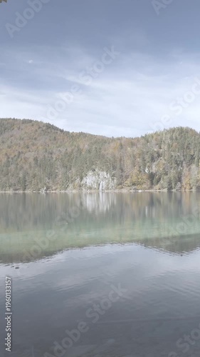 Gentle water ripple in alpine lake with autumn forest foliage offering peaceful wilderness reflection