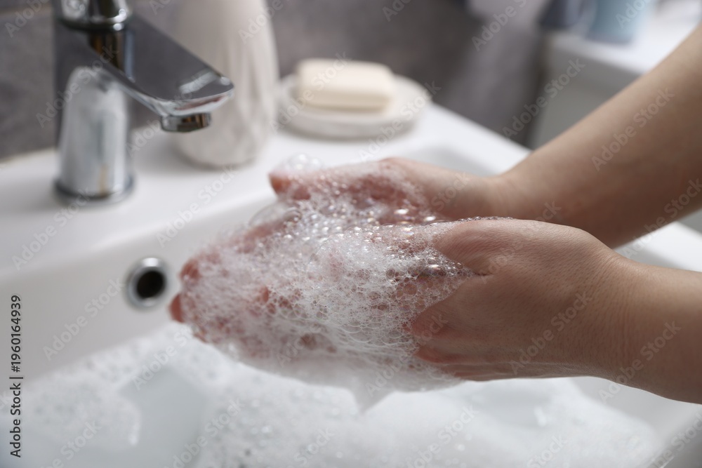 Fototapeta premium Woman washing hands with soap near white sink in bathroom, closeup