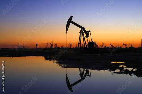 The oil pumping unit is operating in the evening outdoors