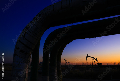 The oil pumping unit is operating in the evening outdoors