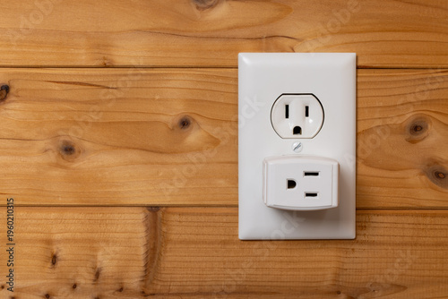Electrical Outlet with Adapter On A Wood Wall