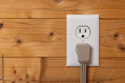Electrical Outlet with Power Cord On A Wood Wall