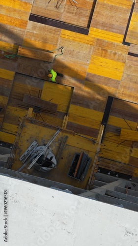 Aerial drone shot looking straight down at two construction workers installing steel reinforcement on formwork deck, showcasing structural preparation and active building process.